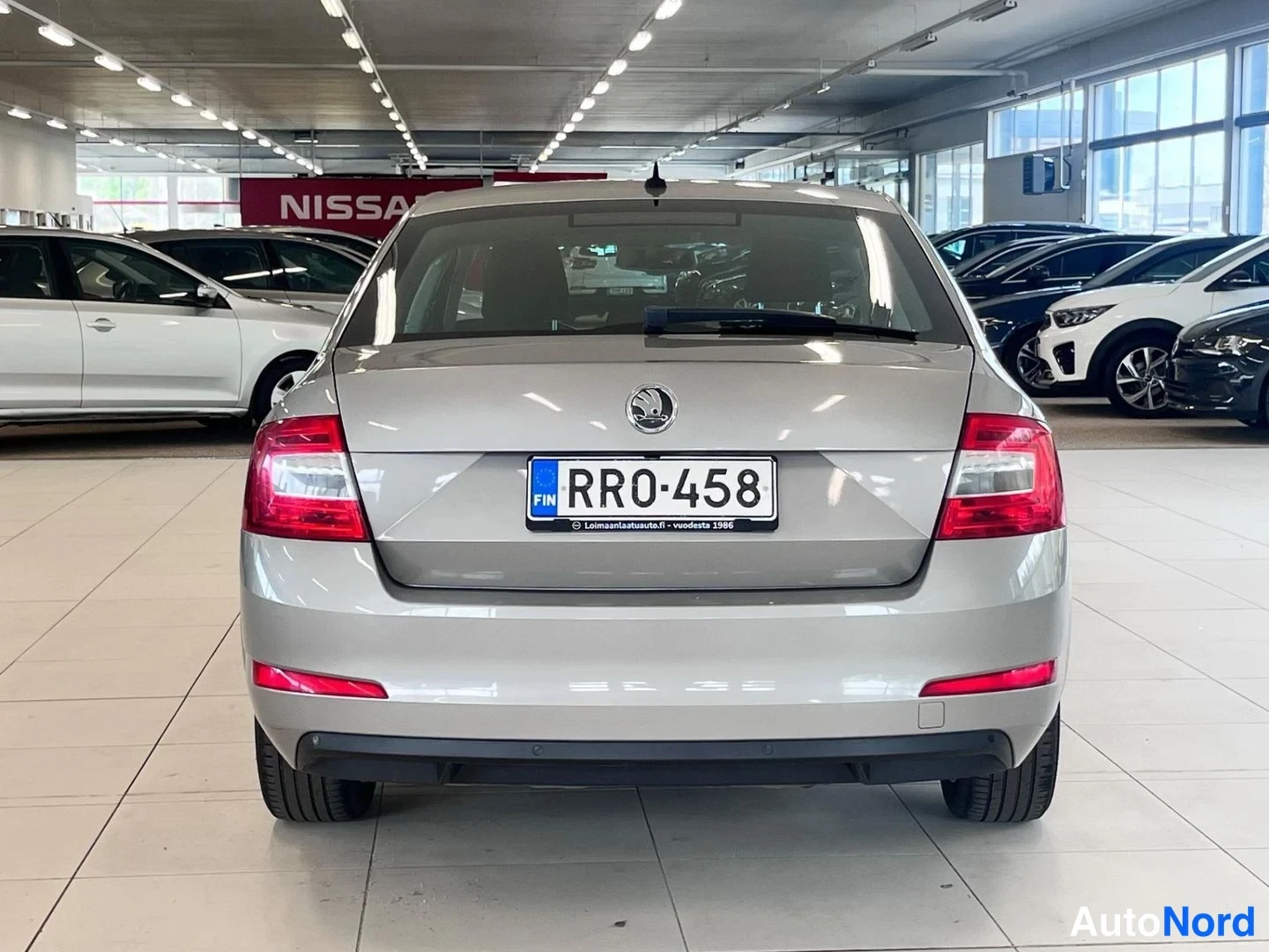 Takaa: Auton takaosa suoraan takaa: hopea Skoda, rekisterikilpi RR0-458, punaiset takavalot ja Nokian-renkaita.
