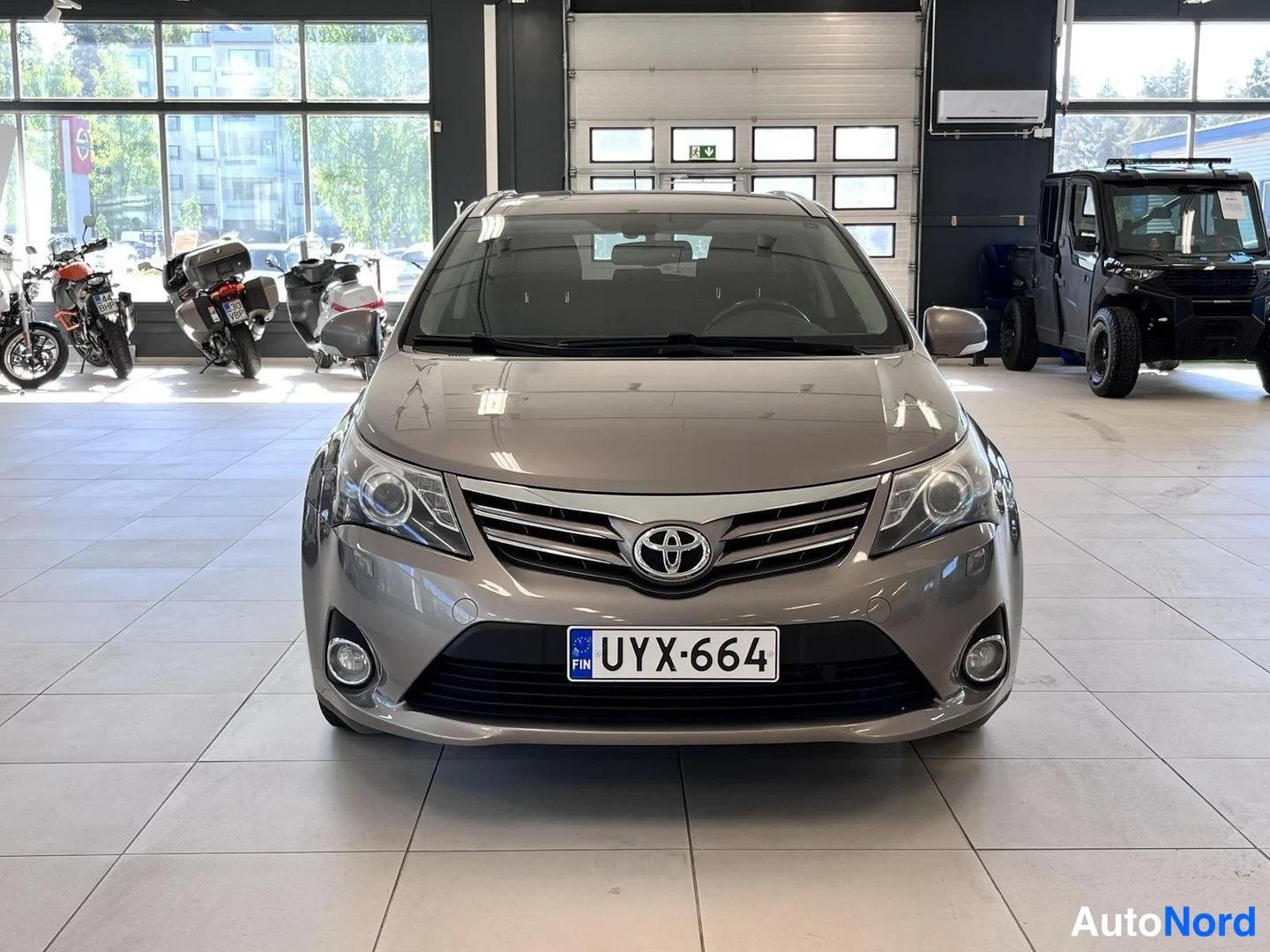 Edestä: Toyota Avensisin etupää suoraan edestä, harmaanbeige, rekisteritunnus.