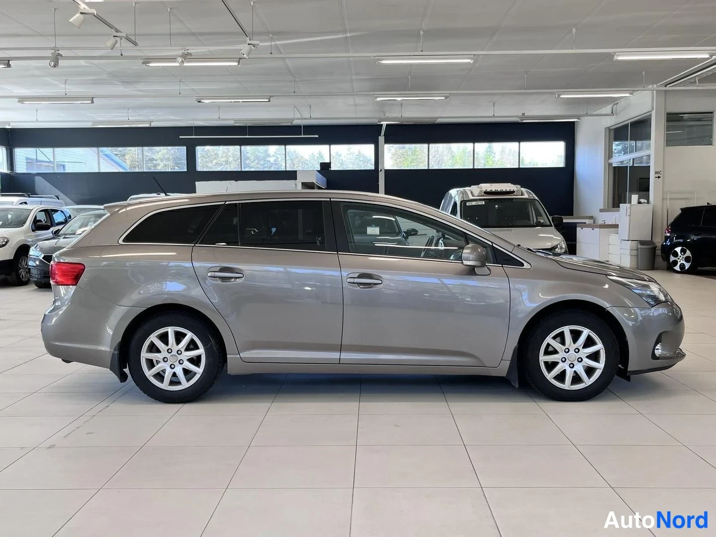 Sivulta: Toyota Avensis -farmarin sivuprofiili vasemmalta, harmaanbeige värinen.
