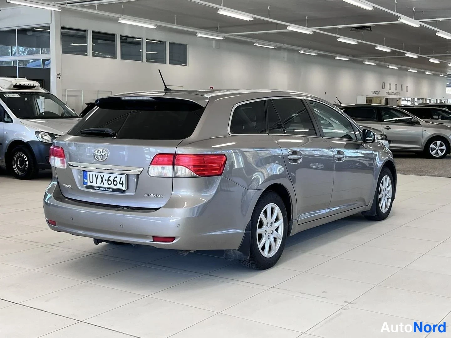 Takaviisto: Toyotan takakulmanäkymä sisätiloissa; rekisteri ja Avensis-merkintä näkyvät.