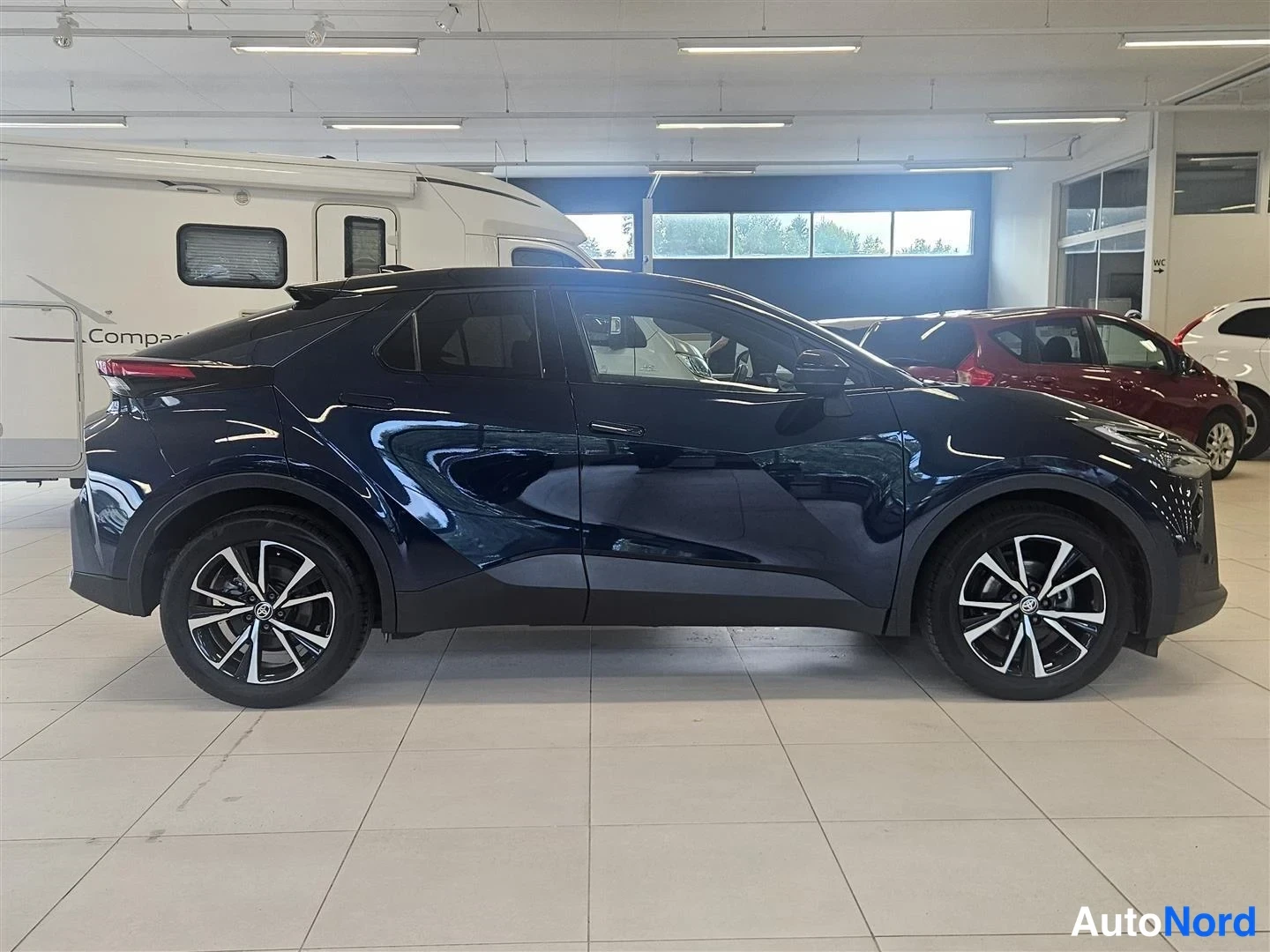 Sivulta: Toyota C-HR:n sivuprofiili kuvattuna sisätiloissa, kaksiväriset alumiinivanteet.