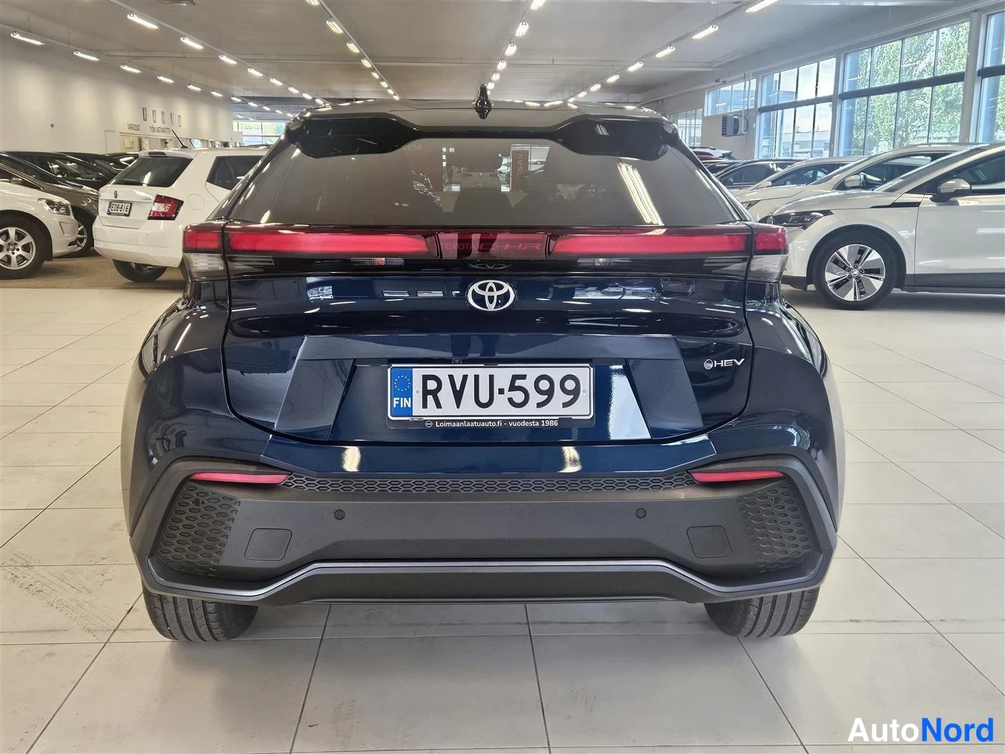 Takaa: Tummansinisen Toyota C-HR:n takaosa suoraan takaa, rekisterikilpi ja HEV-merkintä.