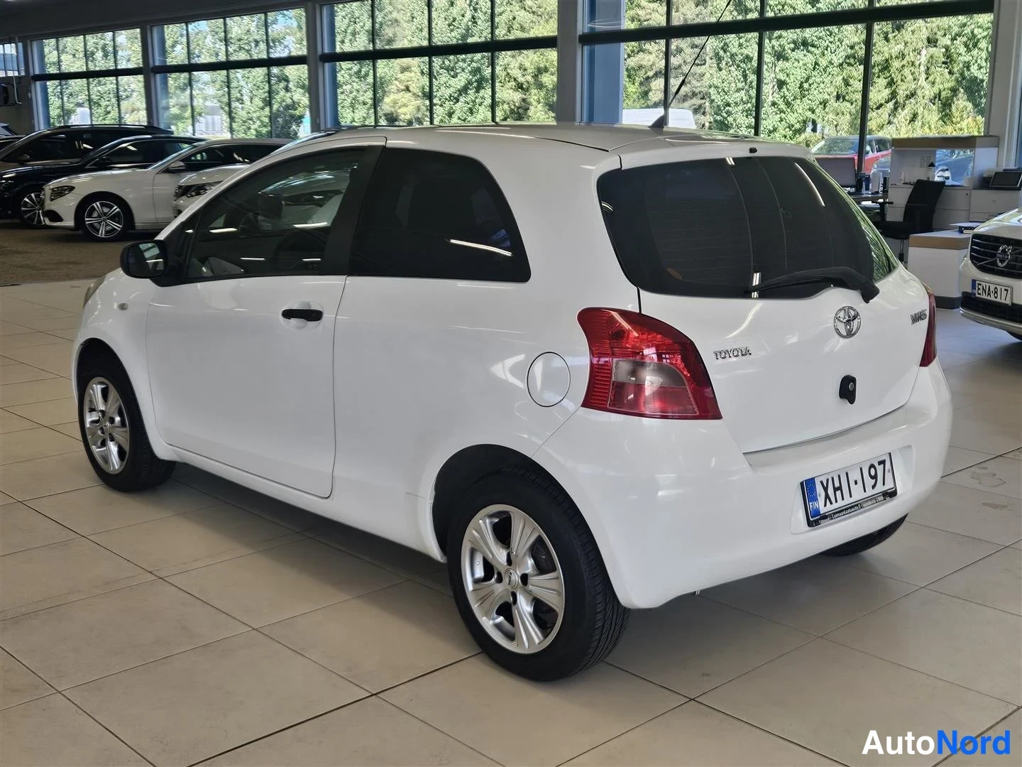 Takaviisto: Valkoisen Toyota Yarisin takakulma vasemmalta, rekisteritunnus.