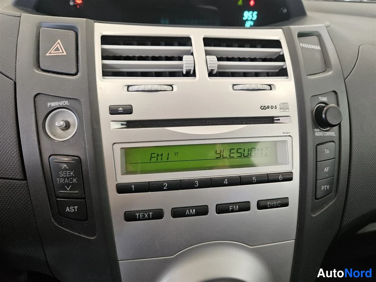 Muu: Lähikuva kojelaudan radiosta ja ilmastointisuuttimista: näytössä lukee FM1 ST ja YLESUOMI, lisäksi nappeja kuten TEXT, AM, FM, DISC, TA, AF, PTY, AST ja SEEK TR