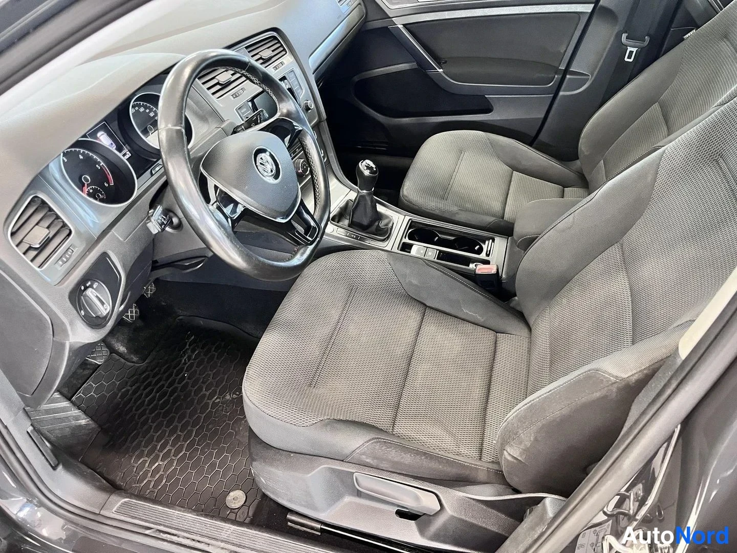 Muu: Auton sisätilat kuljettajan puolelta: VW-ohjauspyörä, analogiset mittarit, manuaalivaihtolaatikon vaihdekeppi, tummat kangasistuimet ja leveät文本.