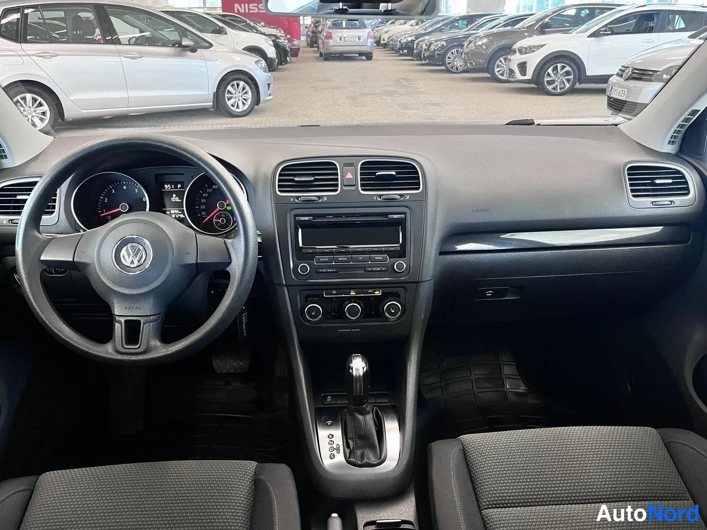 Yksityiskohta: Sisätilan etupuolen panoramakuva: Volkswagen-ohjauspyörä, kojetaulu, radio ja manuaalinen vaihtoehto, muovimatot ja etupenkit.