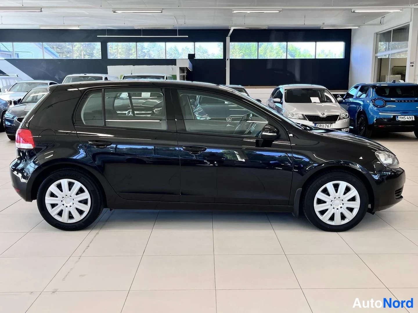 Sivulta: Volkswagen Golfin sivuprofiili showroomissa, väri musta.