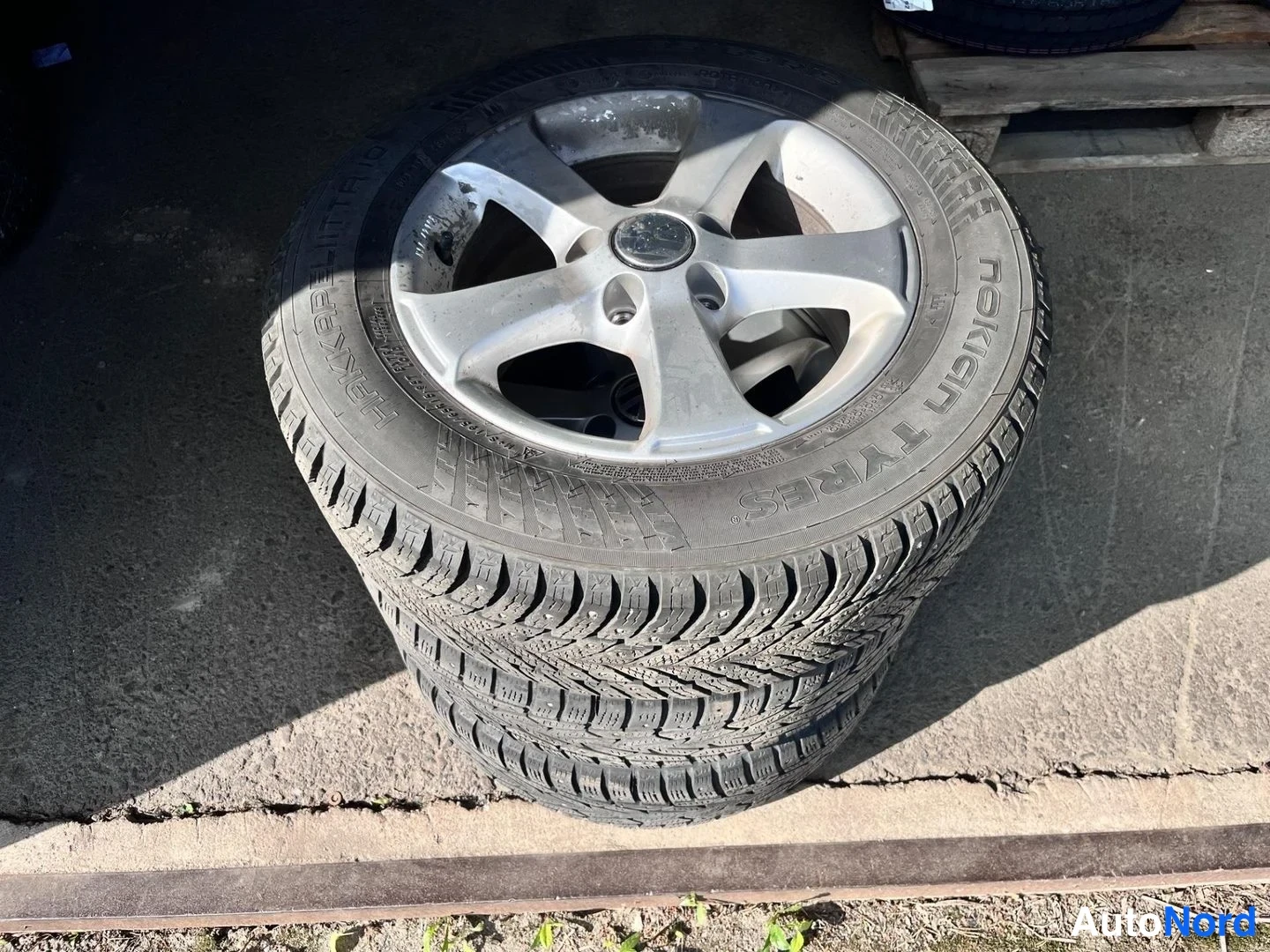 Yksityiskohta: Kaksi Nokian-renkasta pinossa, päällimmäinen hopeisella viisipuomaisella vanteella