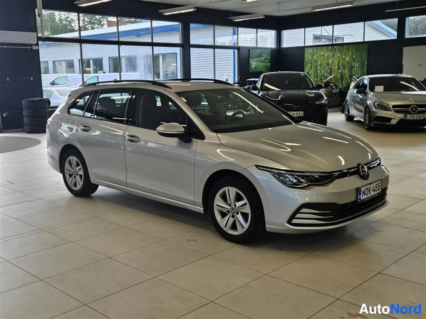 Etuviisto, nokka oikealle: Farmariauto autosalonin lattiassa, etupää ja vasen kylki näkyvät, rekisterikilpi N0K-455.