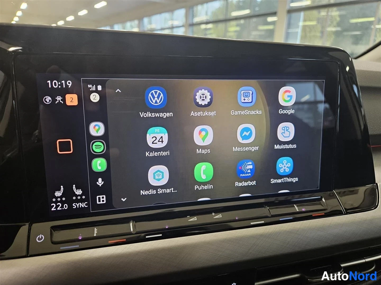 Muu: Auton infotainment-näytön sovellusvalikko sovelluksilla Volkswagen, Asetukset, Google, Maps, Messenger, Kalenteri ja Puhelin; kello 10:19.