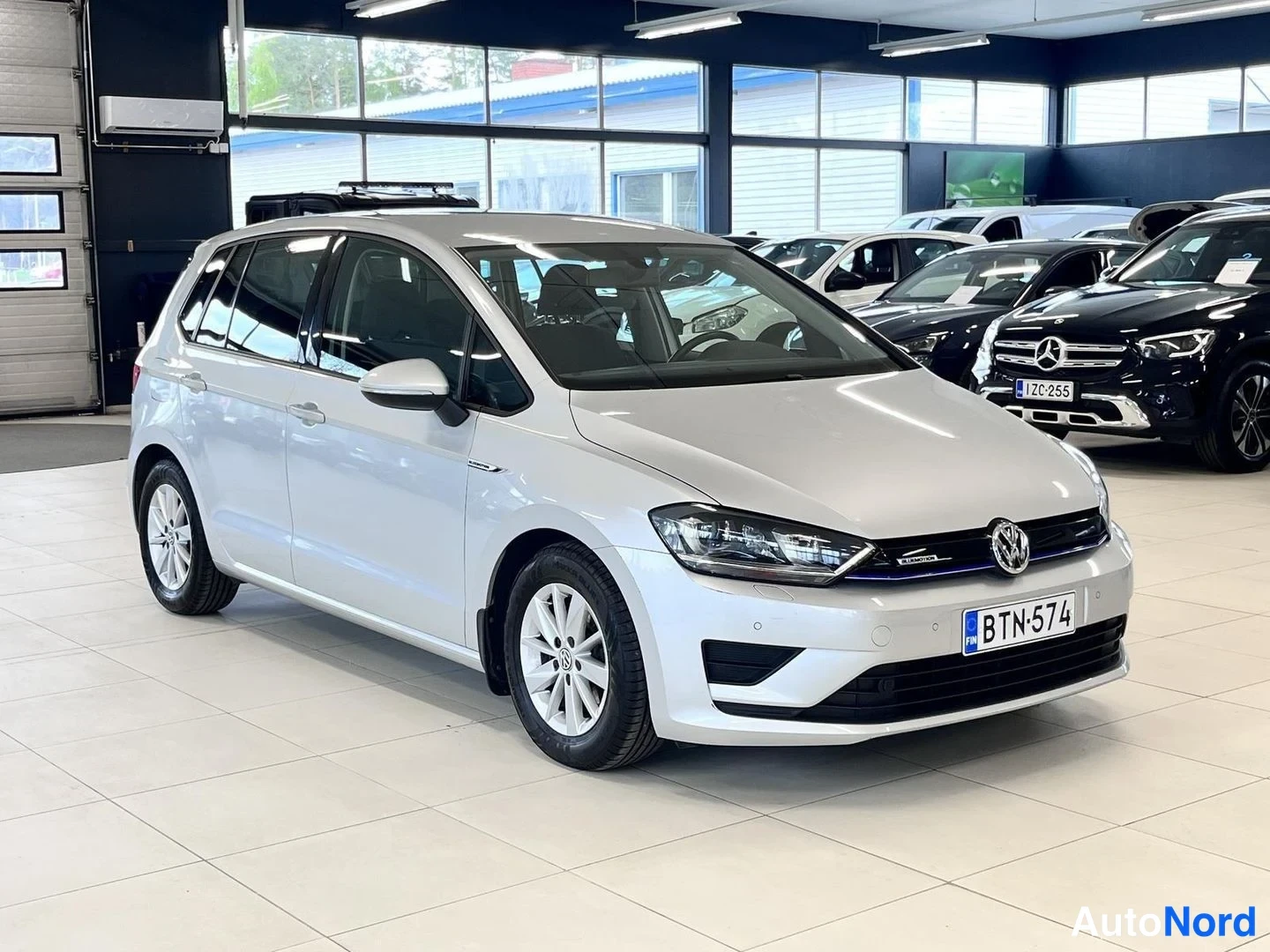 Etuviisto, nokka oikealle: Volkswagen Golf Sportsvan -henkilöauto etuoikealta kuvattuna autonäyttelytilassa.