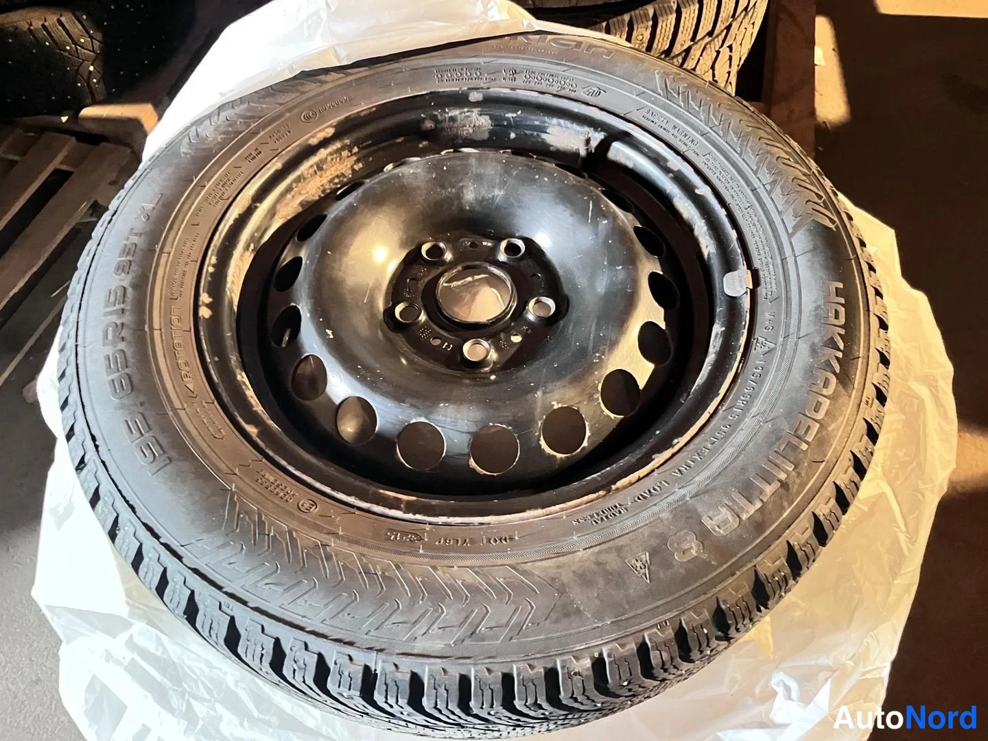 Yksityiskohta: Nokian Hakapeliitta 8 -kumisaappassaan pinnantraktorit ja metallivanner autotallin lattialla.