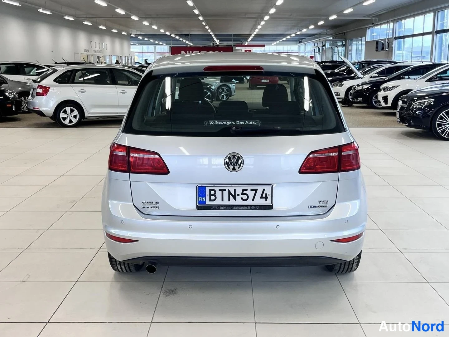 Takaa: Hopeanvärisen Volkswagen Golfin takapää suoraan selvästi kuvattuna autosalissa, rekisterikilpi.