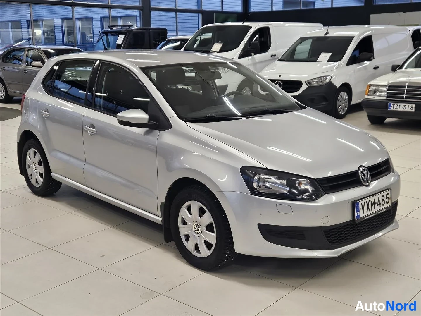 Etuviisto, nokka oikealle: Hopeanvärinen Volkswagen Polo -viistoperä autoa autonäyttelyssä, kuva edestä oikealta.