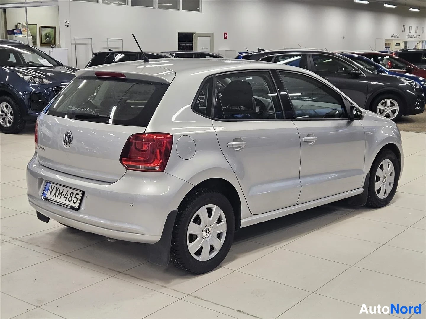 Takaviisto: Hopeanvärinen Volkswagen Polo -viistoperä autosta takaapäin vasemmalle kuvattu kuva autonäyttelyssä.