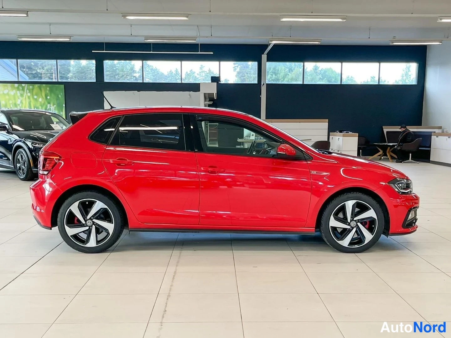 Takaviisto: Punaisen Volkswagen Polon sivuprofiili toisesta suunnasta, takana ja edessä näkyvät valot reunoilla.