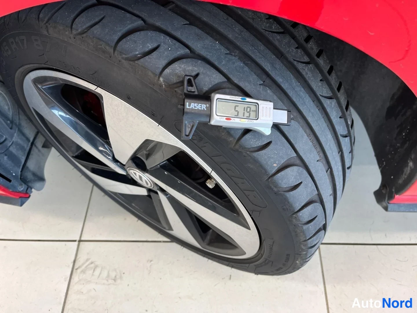 Yksityiskohta: Volkswagen-mallinen kevytmetallivanne ja kesärena; mittaustyökalu näyttää rengasurasyvyydeksi 5,19 mm.