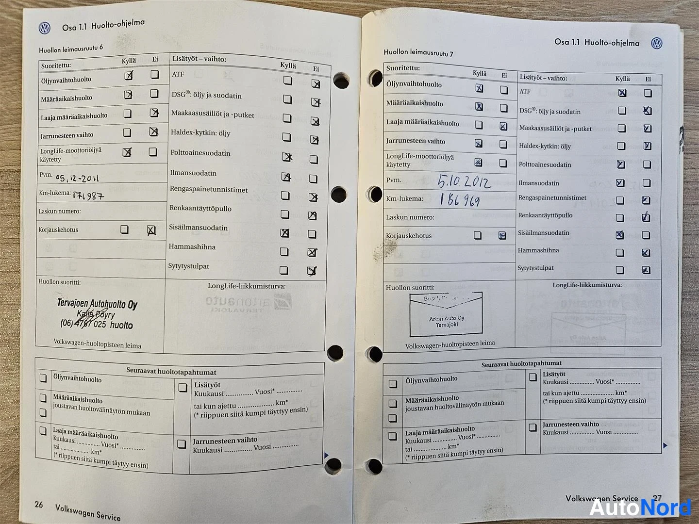 Yksityiskohta: Auki levitetty Volkswagenin huoltokirja, huoltoleimausruudut 6 ja 7 täytettyinä huoltoleimoilla.