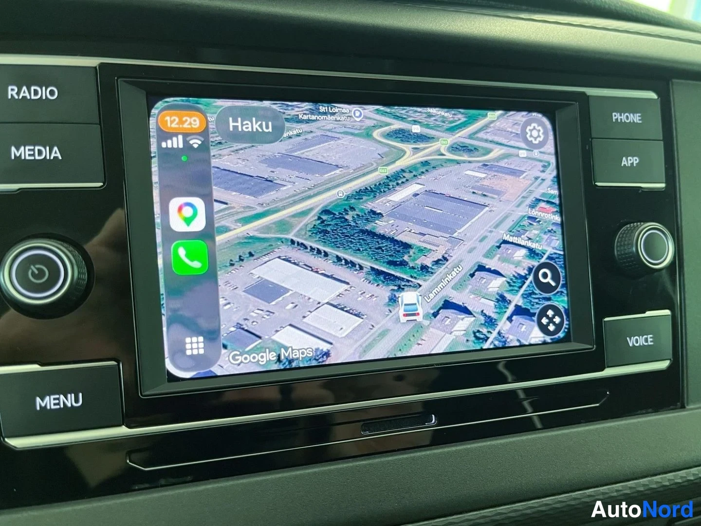Muu: Infotainment-näytön Google Maps satelliittinäkymä Lemminkäisenkadun ja Suurkenttätien alueesta, hakupainike Haku ylhäällä ja CarPlay-sovelluskuvakkeet vasemmall
