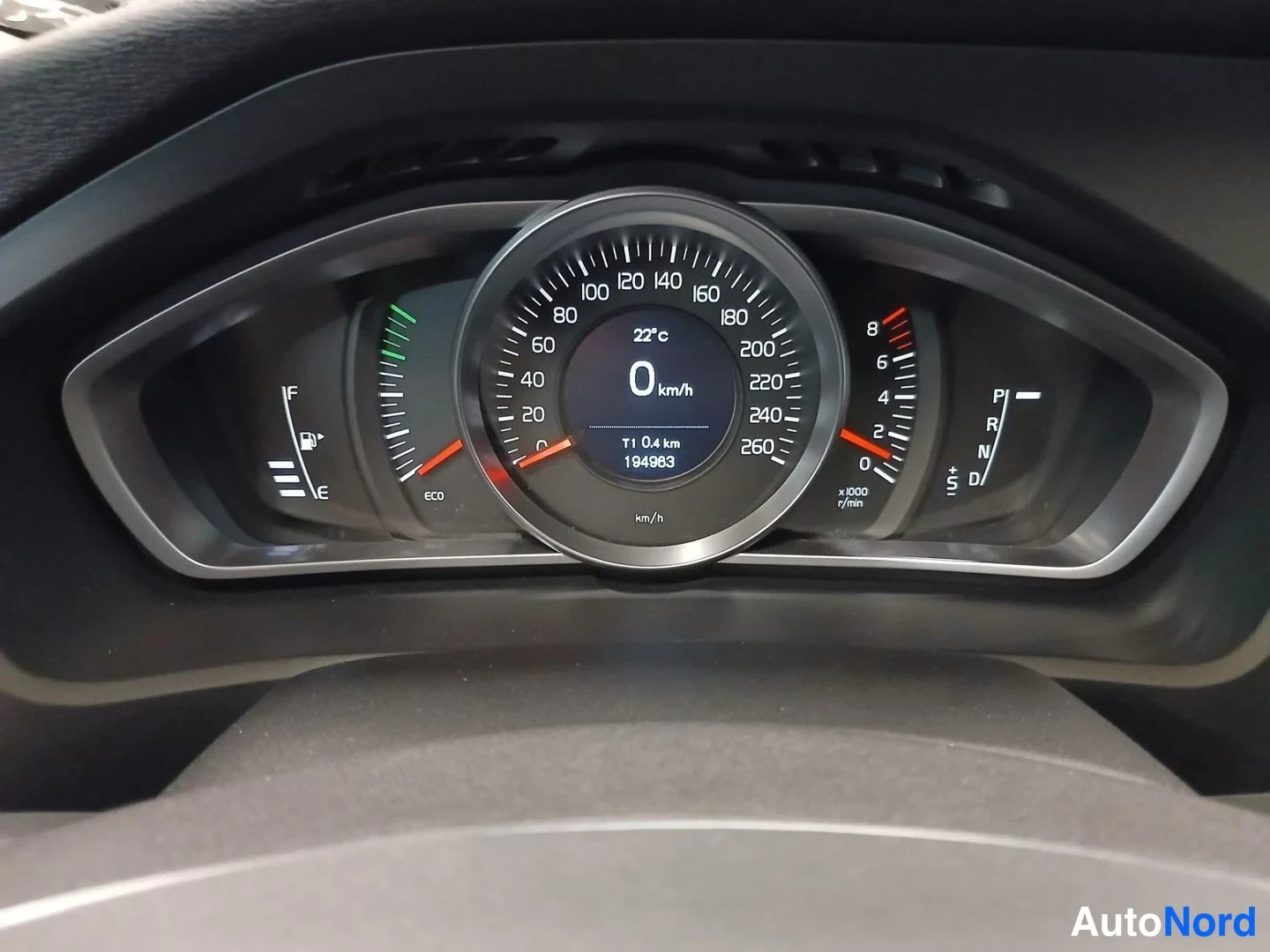 Yksityiskohta: Volvo V40:n kojelaudan mittaristo: nopeusmittari 0 km/h, lämpötila 22 °C, polttoainemittari täynnä, matkamittari T1 0,4 km ja lukema 194 983, automaattivaihteen