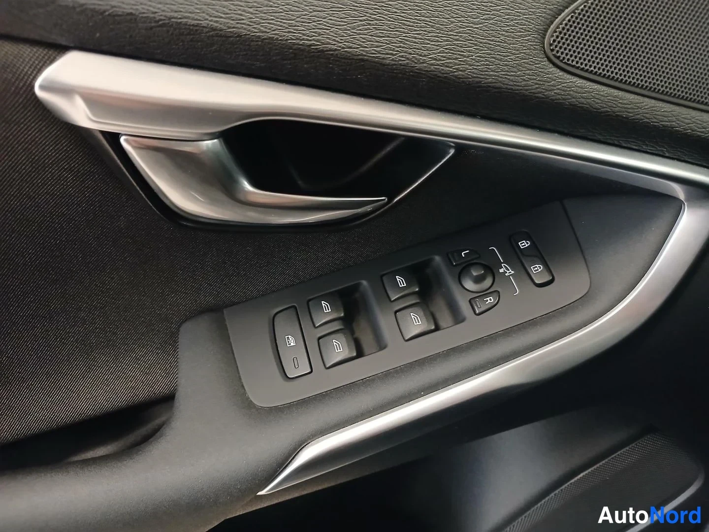 Yksityiskohta: Volvo V40:n oven sisäpaneeli: hopeanvärinen ovikahva, neljän ikkunan kytkin, peilisäädin, lukituksen avaus- ja lukituspainikkeet sekä kaiuttimen hila.
