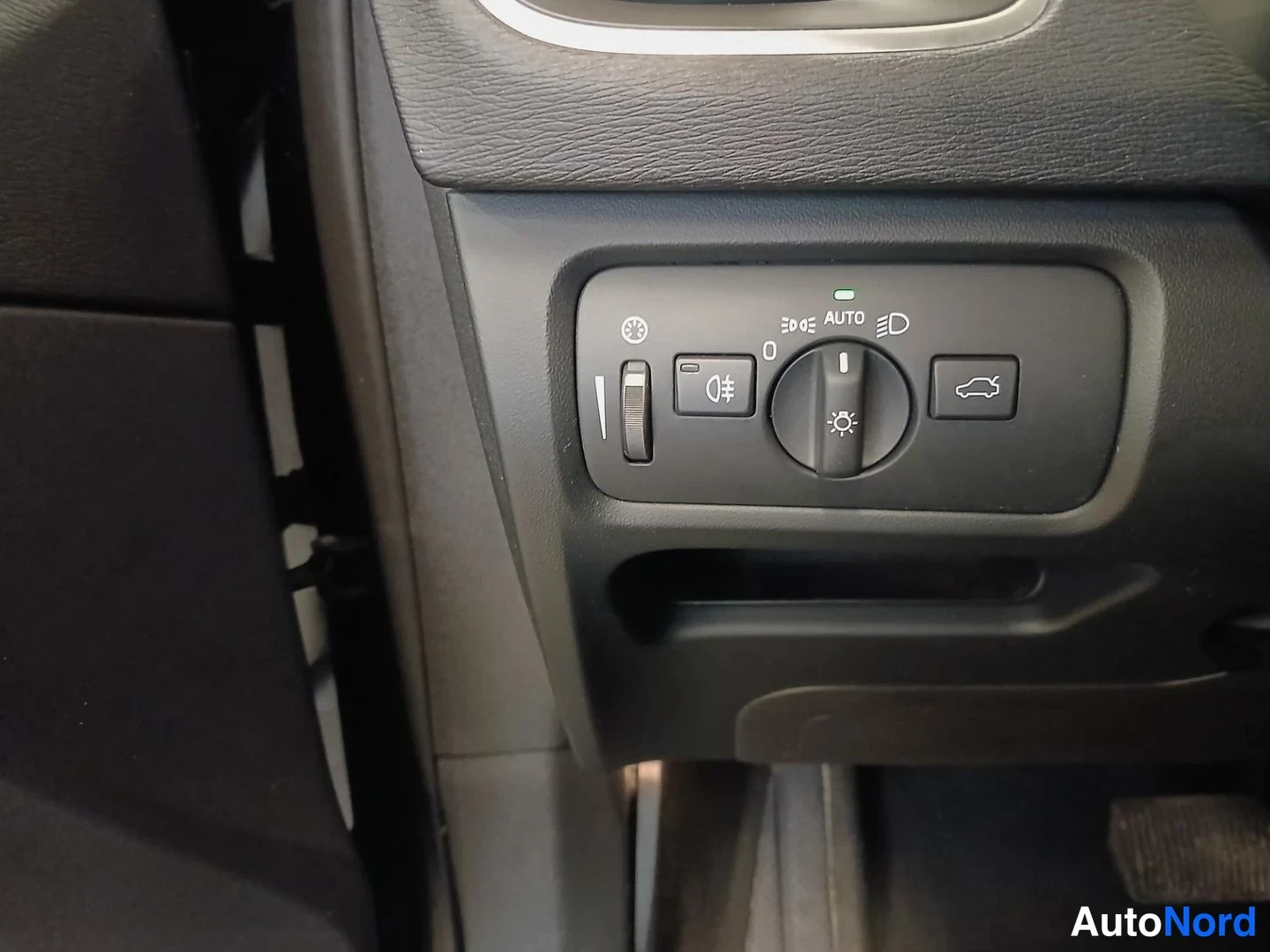 Yksityiskohta: Volvo V40:n ajovalonsäädin: kääntökahva AUTO-merkinnällä, sumuvalon kytkin, ulkovarusteiden säädin sekä vihreä AUTO-valo.