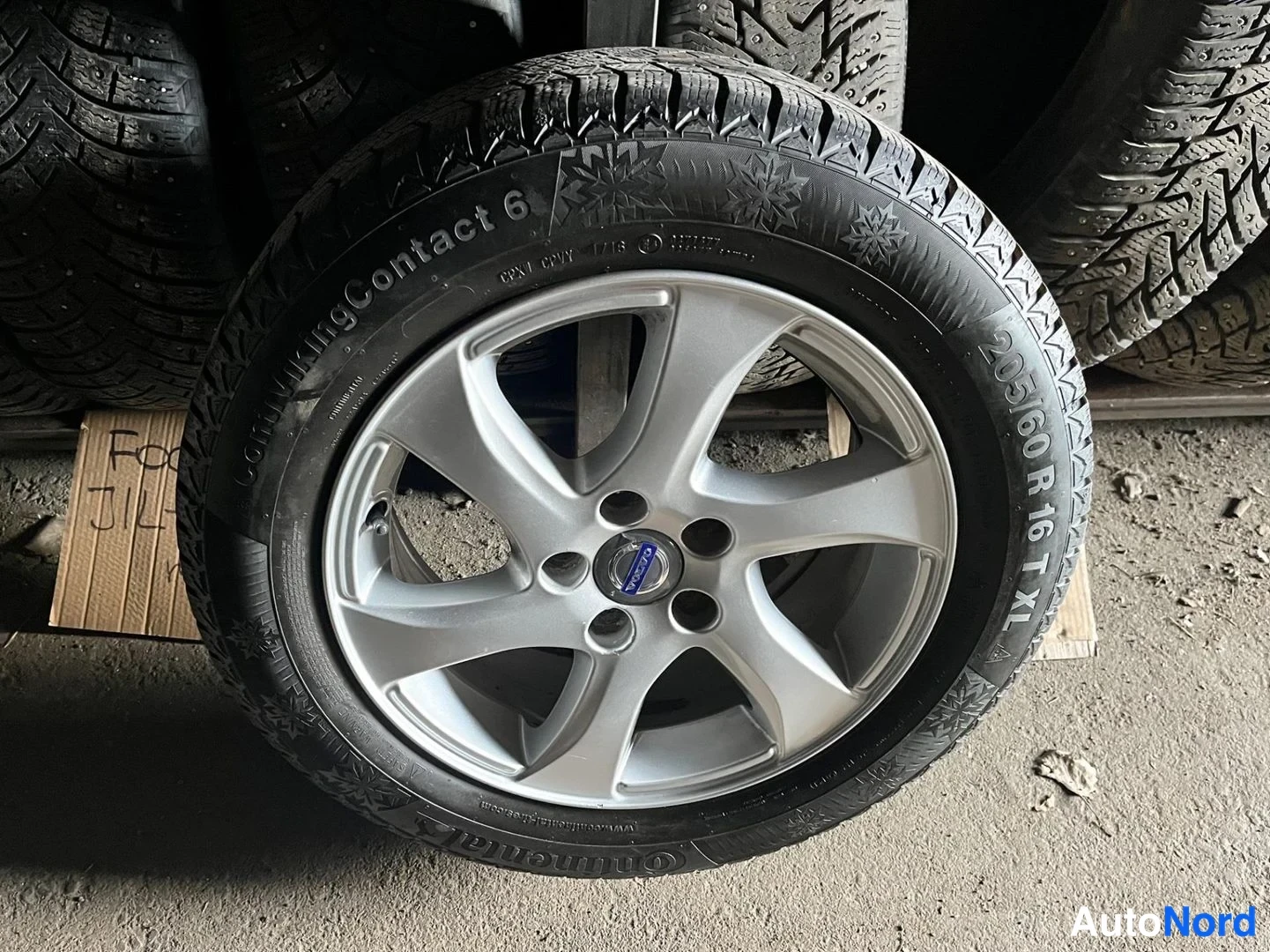 Yksityiskohta: Talvirengas Volvo-napukehällä, Continental VikingContact 6, kokomerkintä 205/60 R 16 T XL, kartongissa käsinkirjoitettua tekstiä.