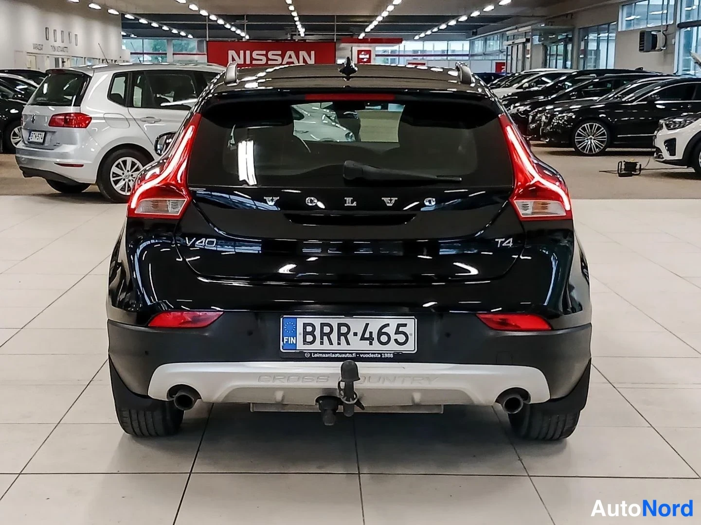 Takaa: Musta Volvo V40 T4 takaa päin kuvattuna autoshopin halleessa; rekisteritunnus ja hinatakavin näkyvissä.