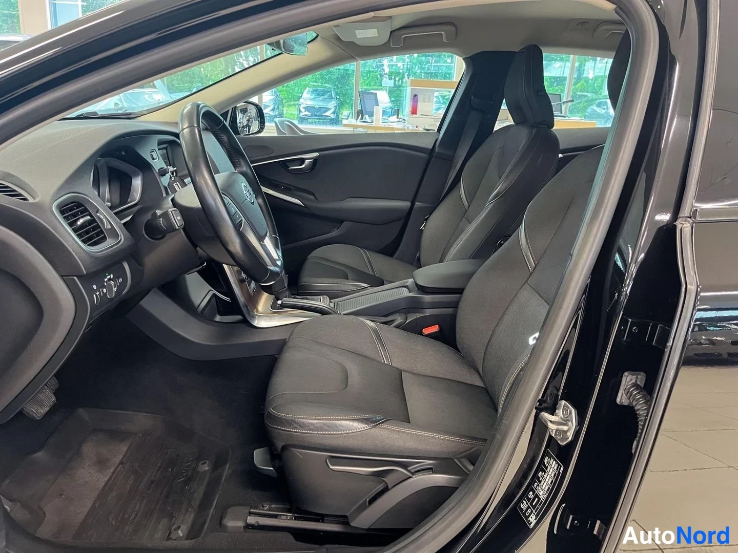 Sivulta: Volvo V40:n kuljettajan puolen etuistuimet ja ohjaamo mustilla kankaanverhoiluilla.
