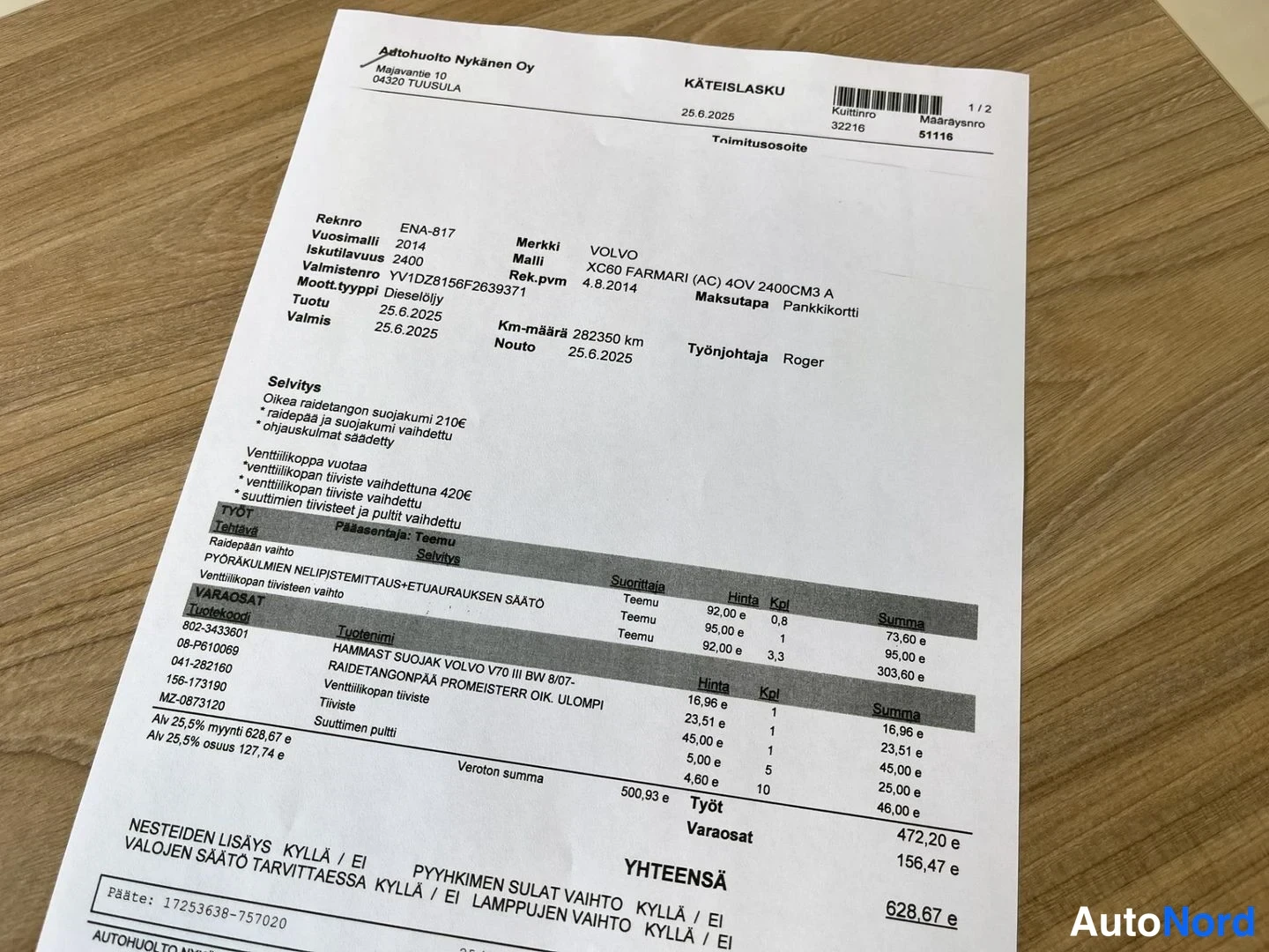 Asiakirja: A photograph of a paper receipt on a wooden table. The document is from Autohuolto Nykänen Oy and is dated 25.6.2025 for a Volvo XC60.