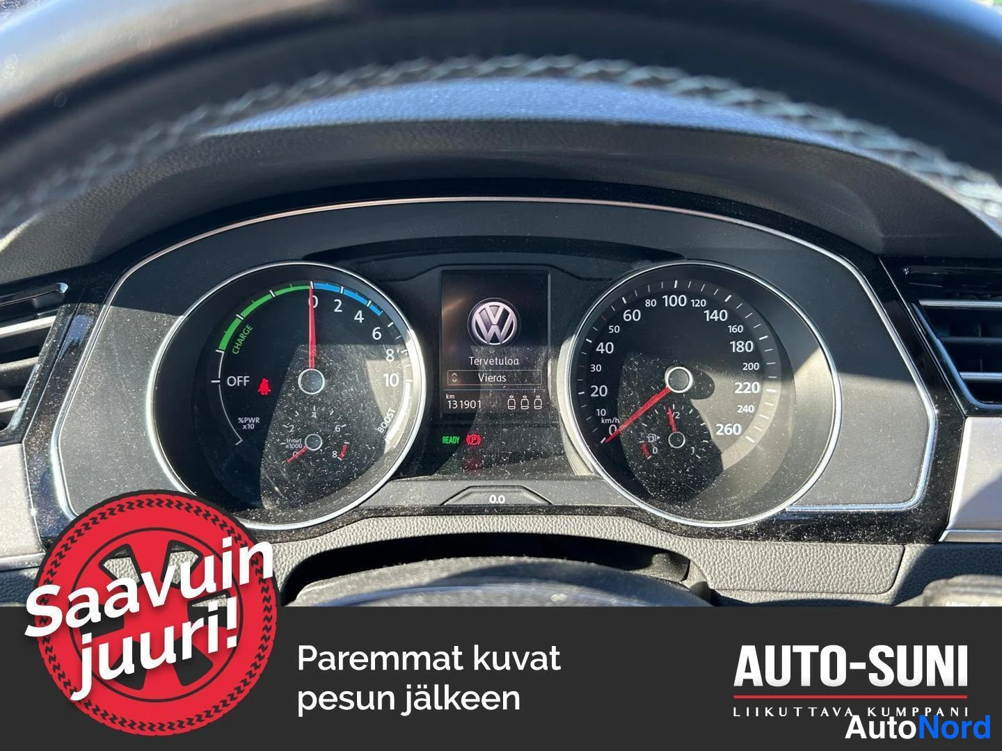 Muu: Auton kojelauta: nopeusmittari ja hybridin lataus-/tehomittari, näytössä teksti 'Tervetuloa Vieras' ja lukema km 131901. Alareunassa myyjän banneri.