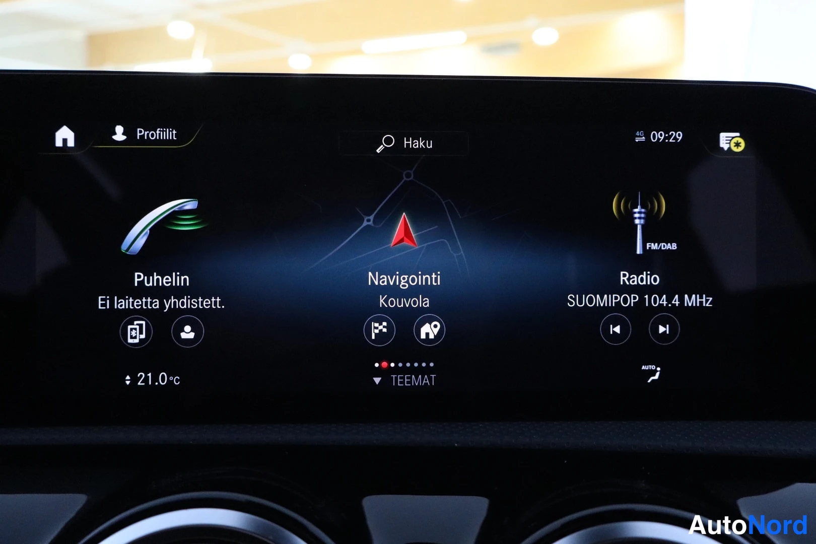 Muu: Keskikonsolin infotainment-näyttö valikoilla Puhelin ('Ei laitetta yhdistetty'), Navigointi (Kouvola) ja Radio (SUOMIPOP 104.4 MHz).