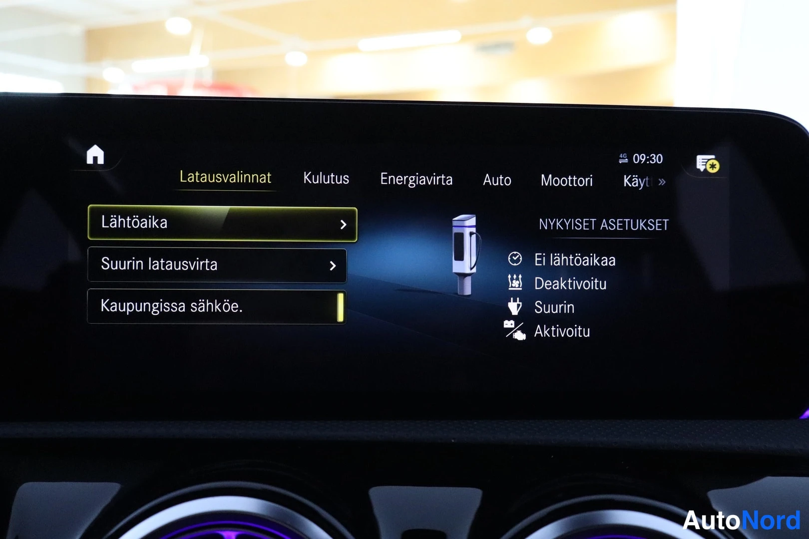 Yksityiskohta: Auton kesk Näytön infotainment-näyttö latausvalinta: valikot Latausvalinnat, Kulutus, Energiavirta, Auto, Moottori; vasemmalla Lähtöaika, Suurin latausvirta ja