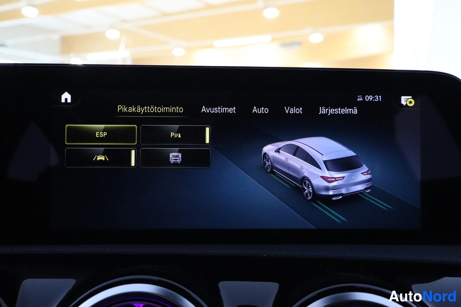 Yksityiskohta: Keskusnäyttö näyttää autollesi Pikakäyttötoiminto-paneelin: ESP, P, LVI ja parkkirijä -painikkeet sekä reaaliaikainen mallikuva CLA Shooting Brake -autosta.