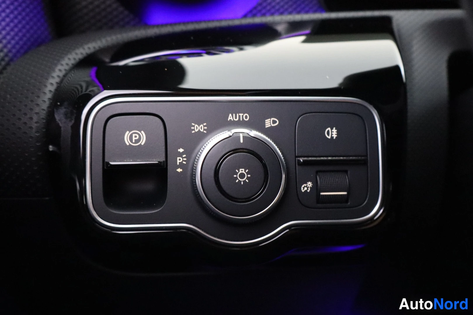 Yksityiskohta: Sisätilan detaljikuva: Mercedes-Benzin valojenohjauskytkinpaneeli, jossa AUTO-merkitty automaattivalot, sumuvalokytkin ja elektroninen pysäytyskytkin (P).