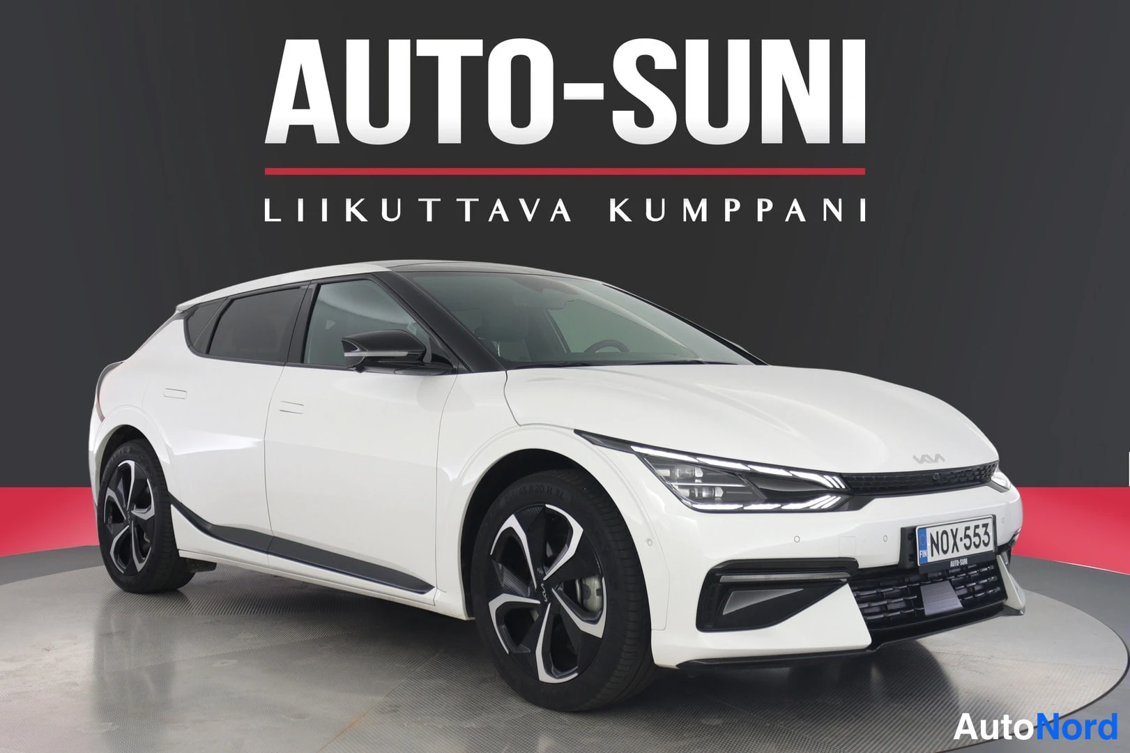 Etuviisto, nokka oikealle: Valkoinen Kia EV6 etukulmasta, keulakkelistä etupyörään näkyvä potkuriteline, rekisteritunnus.