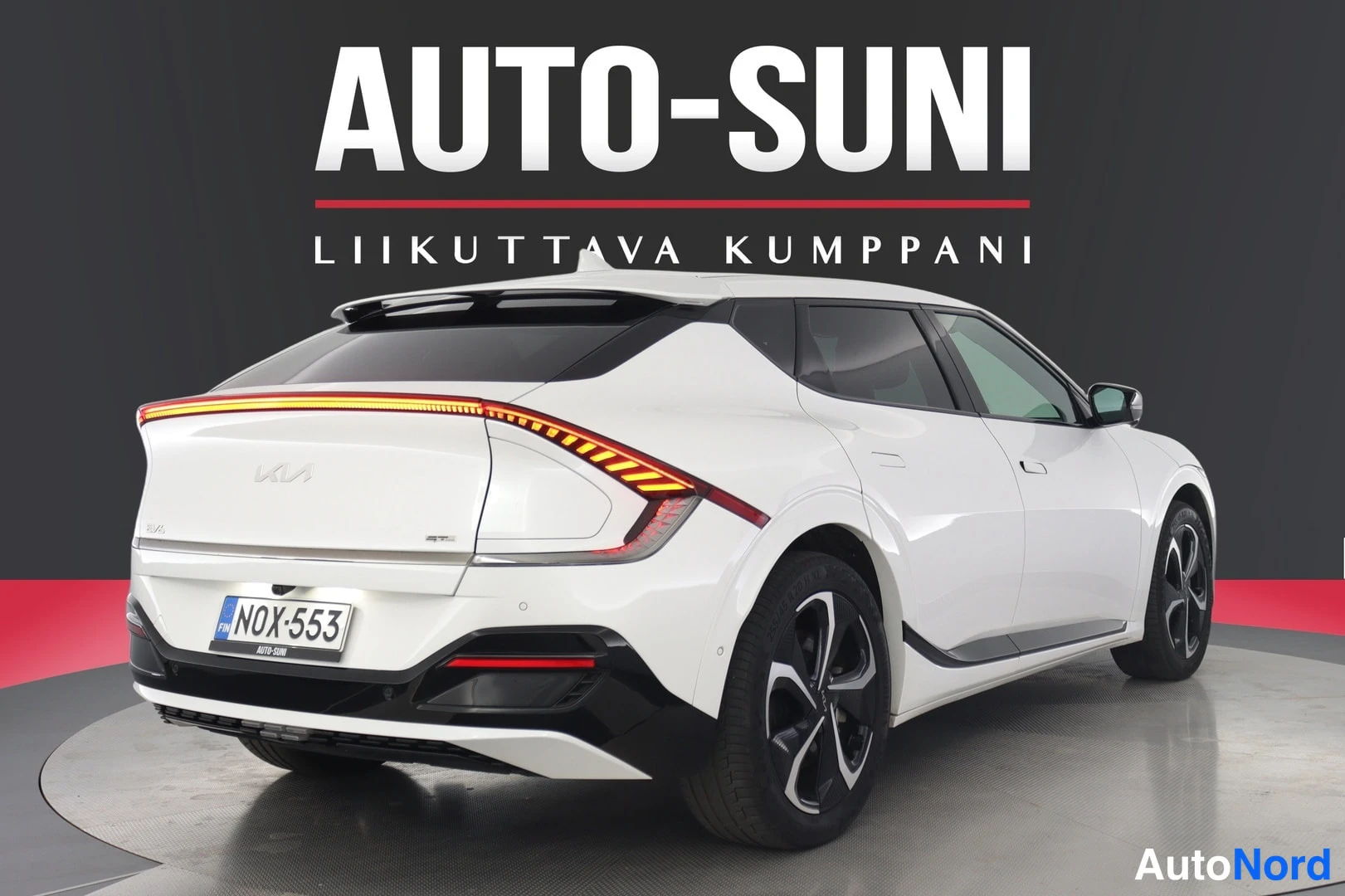 Takaa: Valkoinen Kia EV6 takaovi auki näyttäen sisätilojen ohjauspaneeleja ja tuolitilaa.