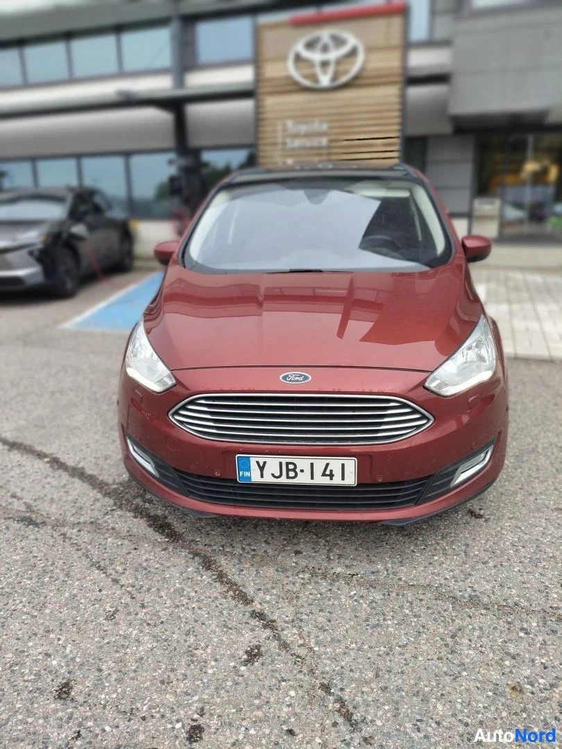 Edestä: Punainen Ford -henkilöauto suoraan edestä, rekisterikilpi.