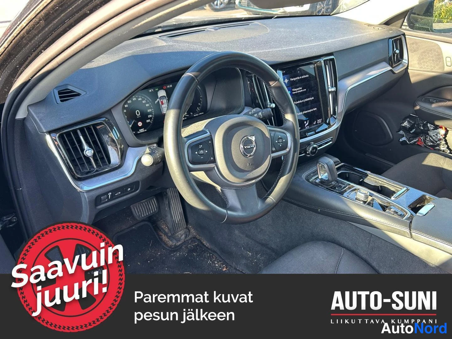 Muu: auton etuistuimelta katsottu kojelauta ja ohjauspyörä, Volvo-merkki ja keskinäyttö näkyvät.