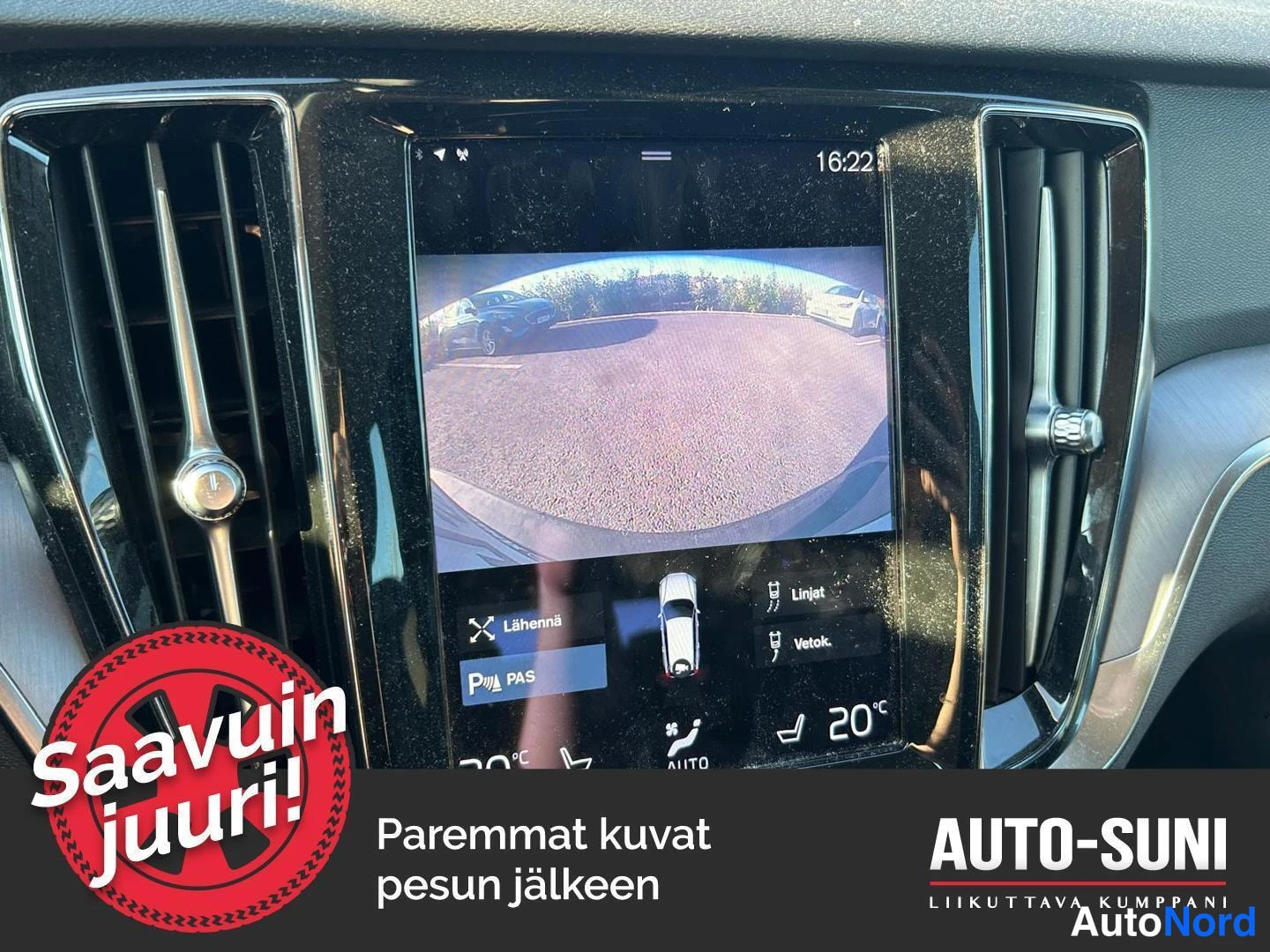 Yksityiskohta: kojelaudan keskellä oleva suuri pystynäyttö, jolla näkyy peruutuskameran kuva parkkipaikasta ja p-funktiovalikko (Läheniä, PAS, Linjat, Vetok.).