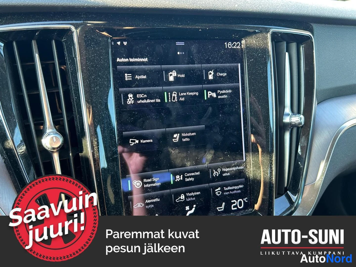 Muu: Auton kojelaudan infotainment-näyttö, jossa on lista autoon liittyviä toimintoja (Kamera, Niskatuen taitto, Road Sign Information, Connected Safety, Nopeusrajoi