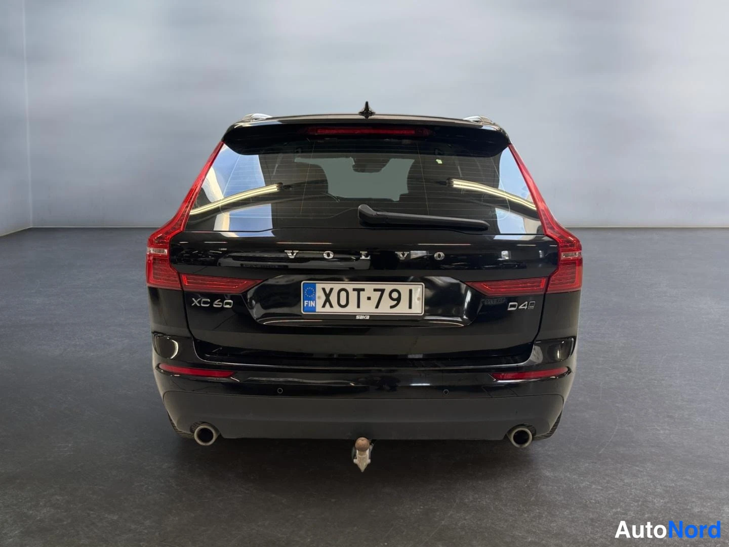 Takaa: Mustan tila-auton takaosa suoraan takaa; XC 60- ja D4-merkit, rekisterikilpi ja vetokoulu näkyvissä.