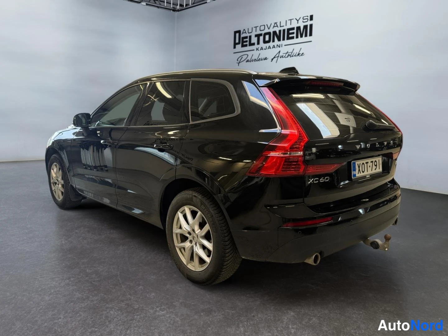 Takaviisto: Mustan tila-auton takakulmakuva oikealta takaa; XC 60-merkintä, rekisterikilpi ja vetokoulu näkyvissä.