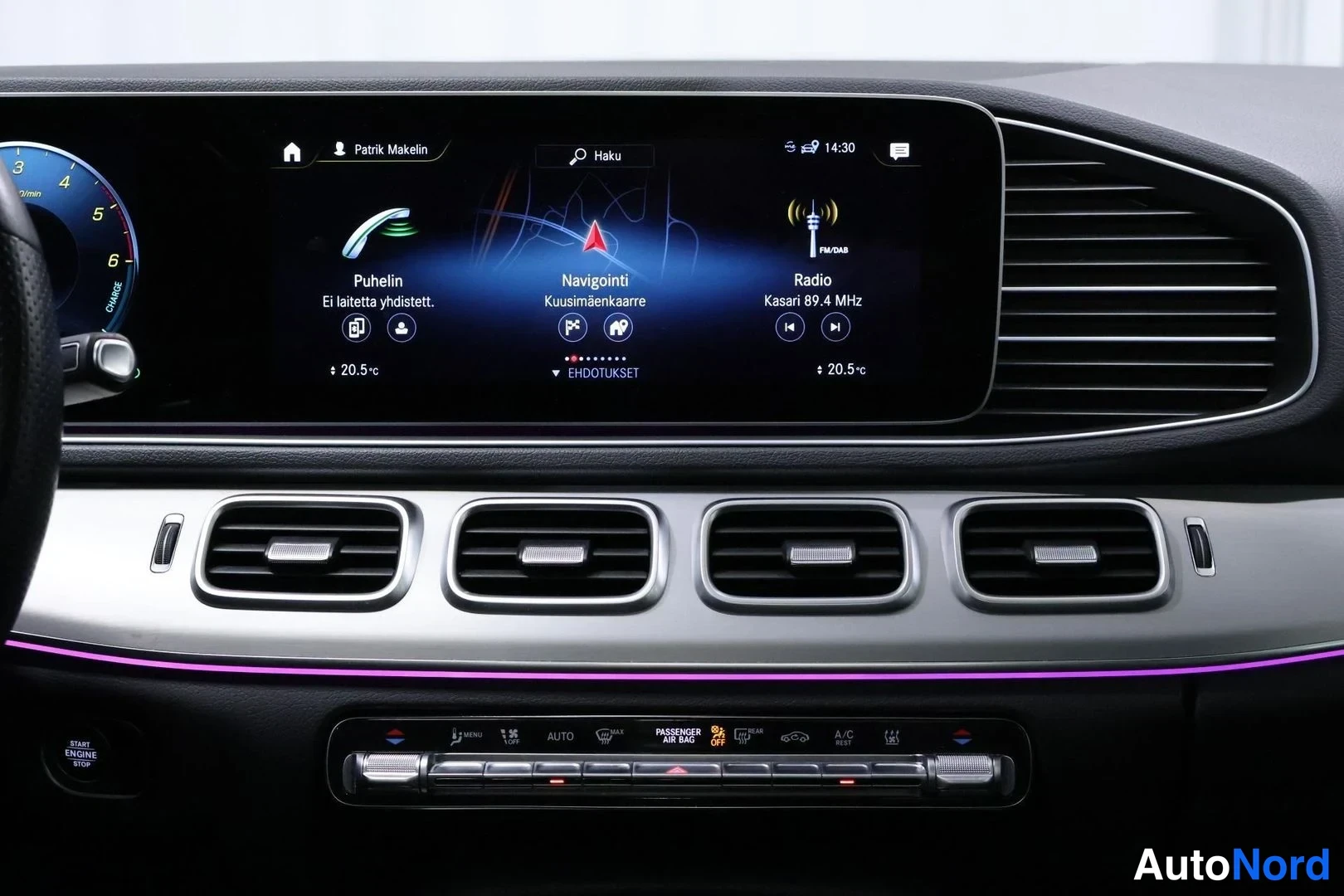 Muu: Kojelaudan keskialue ja infotainment-näyttö, jolla näkyvät Puhelin-, Navigointi- ja Radio-valikot sekä neljä ilmastointiritilää ja obligaattorin säädinpaneli.