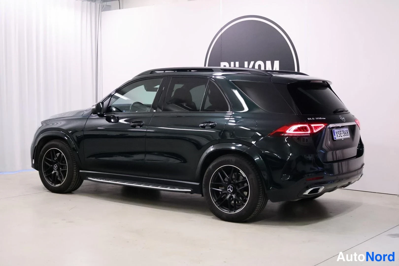 Takaviisto: Takaolkulma mustavalkoinen studio kuva tummanvihreästä Mercedes-Benz GLE 350 de 4MATIC 2023, näkyy konepellin takaa sivusuojaus, takapyörät, tummat kevytmetalli