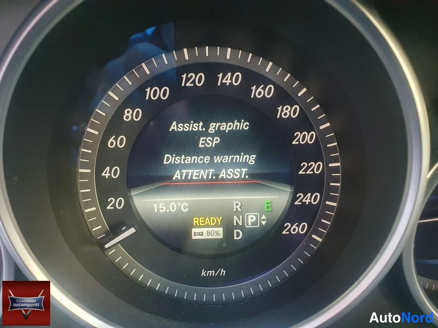 Muu: Mercedes-Benzin nopeusmittari, näytössä apujärjestelmien valikko (ESP, Distance warning, ATTENT. ASST.), 15,0 °C, READY ja P-valinta.