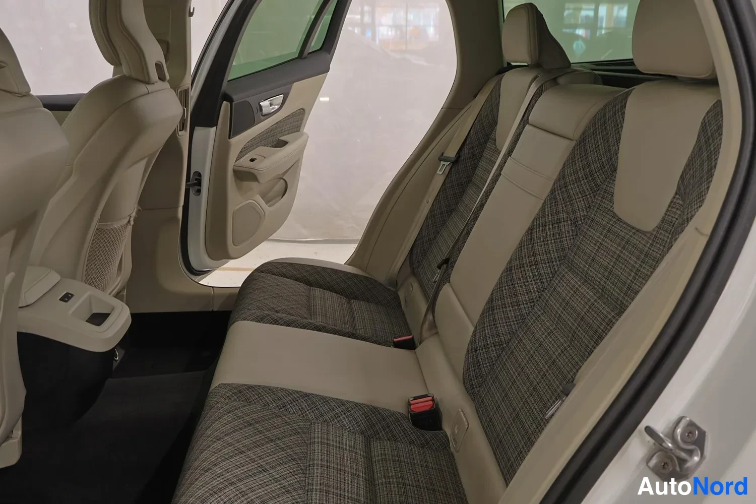 Sivulta: Auton takapenkki sivulta katsottuna: kaksi erillistä takapaikkaa kankaanisilla selkänojilla ja headrest-päätuilla, etuistuinten selkänojat ja takaovin auki.