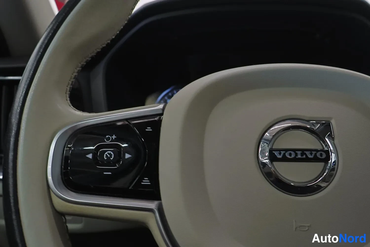 Yksityiskohta: Erittäin lähikuva Volvo-ohjauspyörän merkistä ja monitoiminapeista.