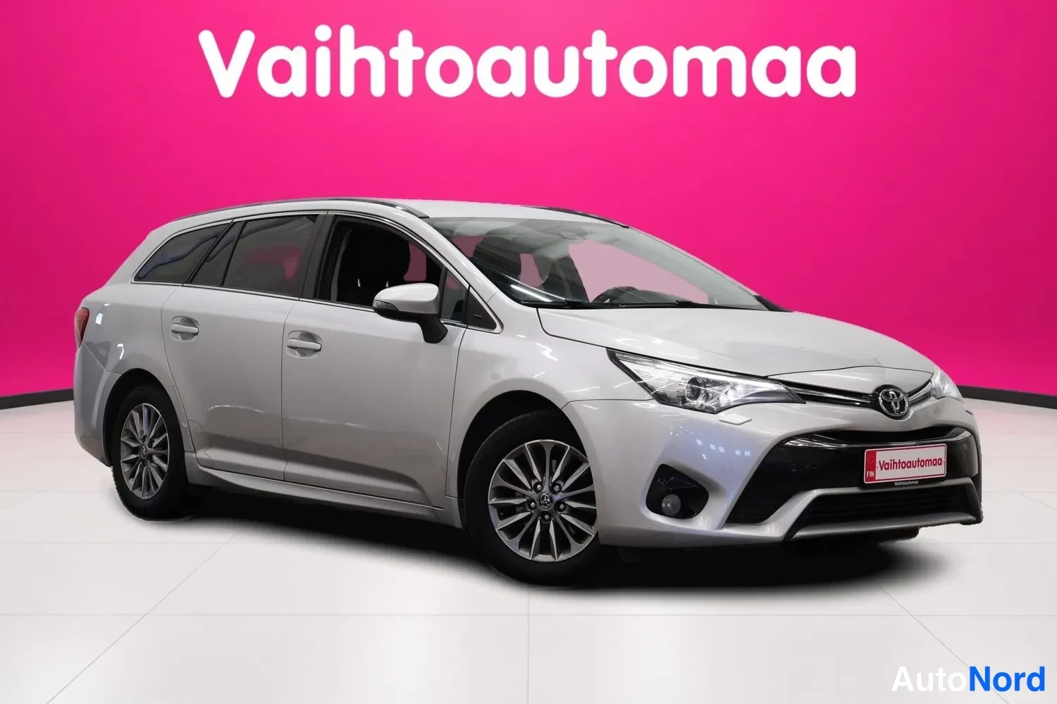 Etuviisto, nokka oikealle: Toyota Avensis Touring Sports -farmari, hopeanvärinen, kuvattu kolmannelta etukanavalta etuosaa ja vasenta sivua esittäen, edessä Toyota-merkki ja sumuva
