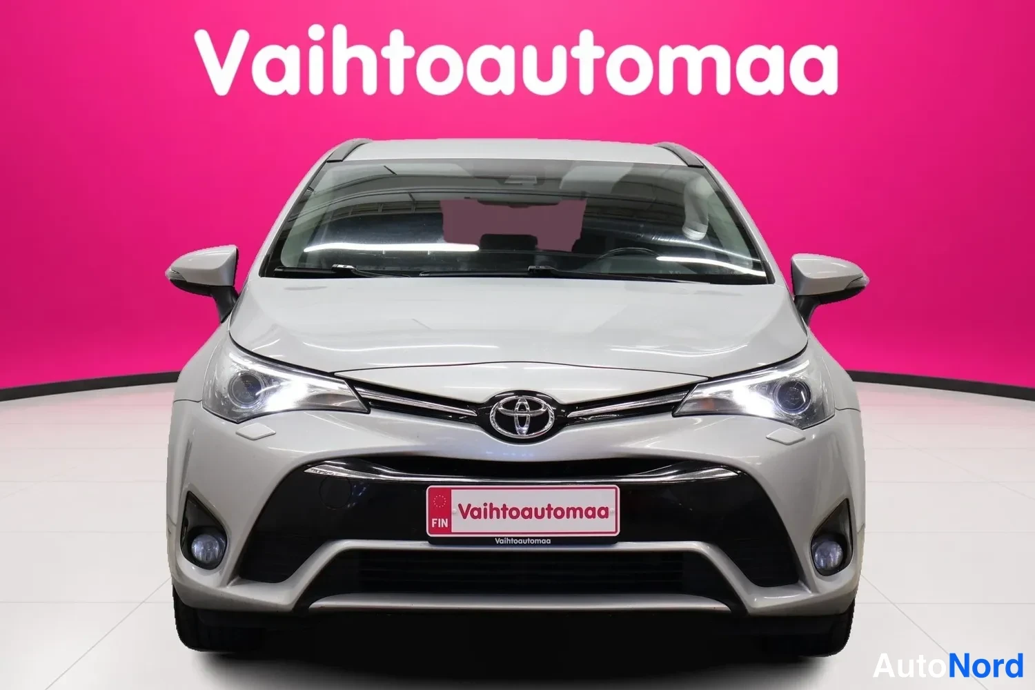 Edestä: Toyota Avensisin keula suoraan edestä kuvattuna: etusäleikkö, Toyota-merkki, ajovalot ja sumuvalot näkyvät.
